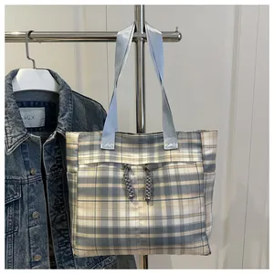 Detail of blue and white checkered tote bag featuring a knotted rope design on the front