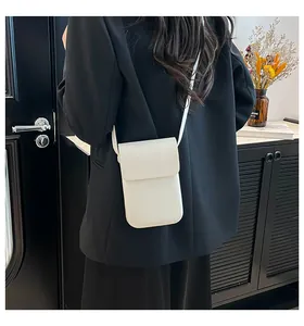 Rear view of a model wearing a minimalist white crossbody phone bag over a dark blazer