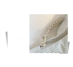Detail of smooth zipper closure with woven pull on beige corduroy dumpling crossbody bag