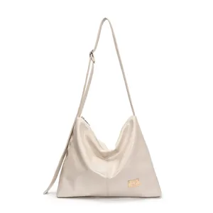Cream hobo shoulder bag in glossy patent leather with adjustable strap and gold logo