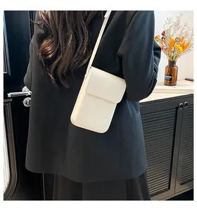 Vertical minimalist ivory crossbody phone bag shown from a back-view model perspective