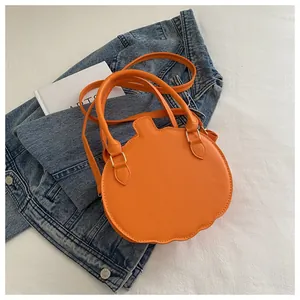 Top view of orange pumpkin shoulder bag placed on denim jacket and white arts book