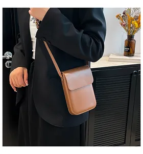 Brown matte PU leather crossbody phone bag on a model wearing a black blazer