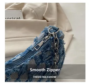 Detail of smooth metal zipper and frayed denim fabric on a vintage shoulder bag