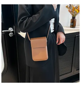 Close-up of a minimalist brown leather crossbody phone bag shown on a model