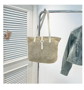 Dettaglio della trama della borsa in paglia intrecciata con cinturino in pelle bianca