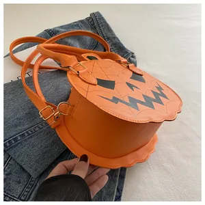 Detail of orange pumpkin bag on denim jacket with shoulder strap and jack-o'-lantern face