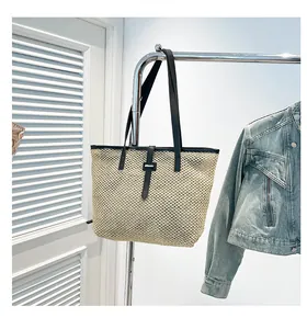 Dettaglio della borsa tote in paglia intrecciata con spalline in pelle nera e fibbie