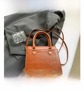 Close-up of crocodile embossed texture on luxury orange brown tote bag with metal buckles