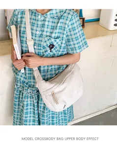 Close-up of off-white corduroy dumpling bag with adjustable strap on a model