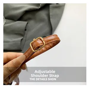 Macro detail of adjustable brown faux crocodile leather strap with gold metal buckle