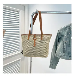 Dettaglio della borsa tote in paglia intrecciata con manici in finta pelle marrone