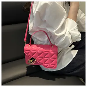 Detail van de rozerode gewatteerde crossbodytas met asymmetrische flap en gouden sluiting