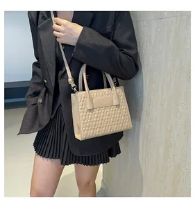 Detail der beige gesteppten Umhängetasche mit geometrischem Muster, gehalten von Modell