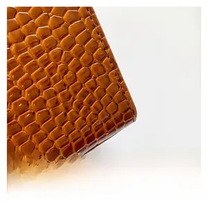 Detail shot of brown crocodile embossed leather with glossy finish and precise stitching