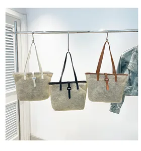 Tre borse shopping in tessuto color crema, nero e marrone appese a un supporto metallico