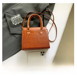 Detail view of brown crocodile texture handbag with detachable shoulder strap and handle