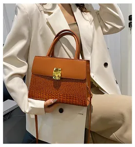 Détail d'un sac à main marron avec relief crocodile et boucle géométrique dorée