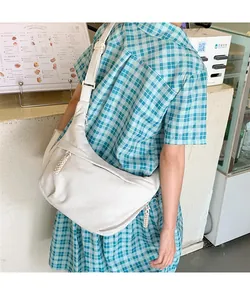 Detail view of white corduroy crescent bag with adjustable strap and textured fabric