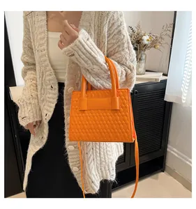 Detail der orangefarbenen gesteppten Handtasche aus Kunstleder mit Rautenmuster und Griffen