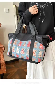 Detalle del bolso de viaje grande con estampado de dibujos y cremallera roja