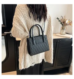 Detail einer schwarzen gesteppten Ledertasche mit Tragegriff und goldenen Beschlägen