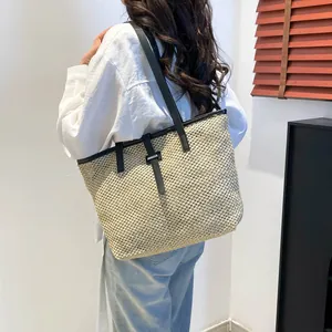 Grande borsa tote intrecciata con spalline in pelle nera indossata da una modella per vacanza