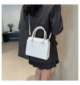 White crocodile texture tote bag worn crossbody on a professional grey blazer outfit