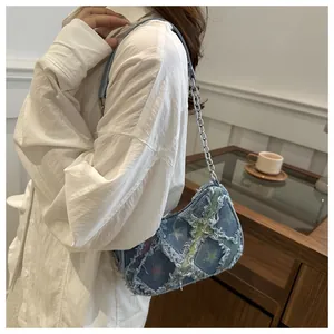 Detail of blue denim shoulder bag with star print patterns and frayed edge textures