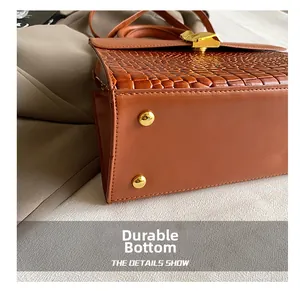 Detail view of the brown crocodile pattern handbag base with four golden metal feet studs