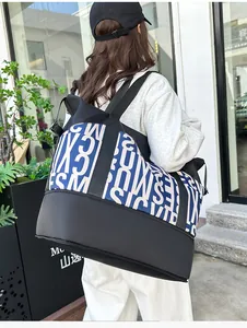 Detalle de un bolso de viaje grande con letras en contraste y correa de tejido negro