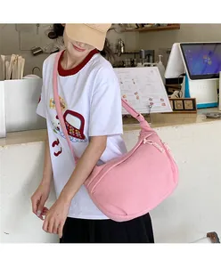 Pink corduroy crescent shoulder bag with wide strap shown on model in a casual setting