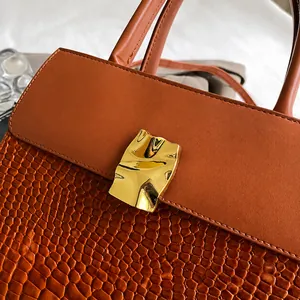 Detail view of dark brown faux crocodile texture handbag with golden metal lock