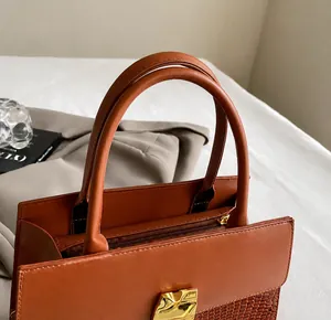 Detail showing high-quality brown crocodile embossed leather handbag and metal zipper