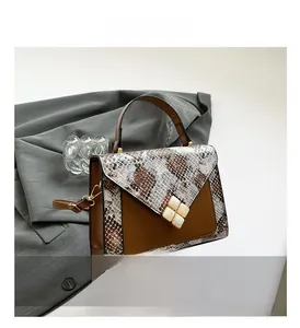 Detail of snake skin texture and envelope fold design on a brown leather handbag