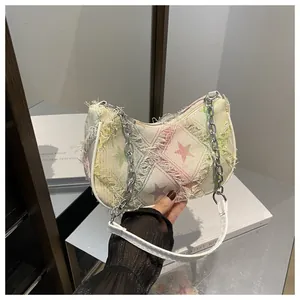 Detail of star-patterned denim bag featuring raw fringe edges and silver chain strap