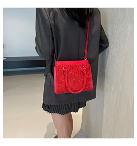 Detail of red crocodile texture tote bag with gold hardware and shoulder strap