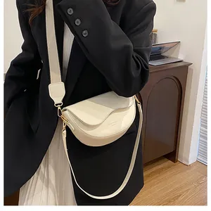 Gros plan du sac besace blanc cassé avec large bandoulière en tissu et boucles dorées