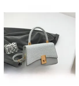 Detail of silver sequined flap and golden twist lock on gray square crossbody bag