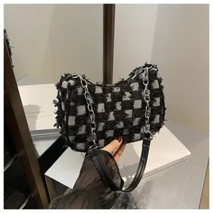 Detail of checkered denim shoulder bag featuring frayed edges and silver chain strap