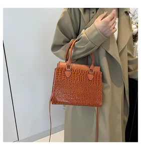 Detailed close-up of brown crocodile texture on a structured leather tote bag