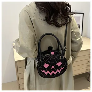 Halloween pumpkin crossbody bag with pink spider web embroidery shown on a green coat