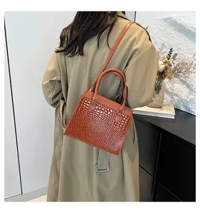 Brown crocodile embossed tote bag styled with a khaki trench coat for a chic autumn look