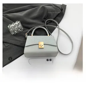 Close-up of light grey handbag with sequin splicing and metallic twist lock detail