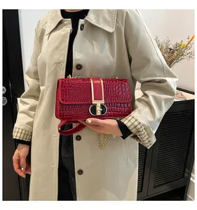 Details einer roten Handtasche mit Krokodilprägung, Goldverschluss und Kettenriemen