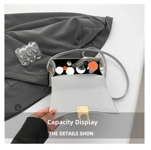 Detail shot of the interior capacity of the grey handbag holding a phone and lipsticks