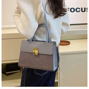Detail of grey crocodile pattern stitching and golden metal buckle on a shoulder bag