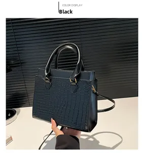 Detail of black crocodile texture tote bag with golden hardware and slim shoulder strap