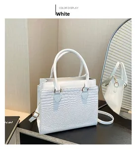 Detail view of white crocodile pattern tote bag with gold hardware and slim shoulder strap