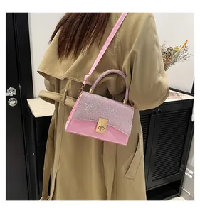 Pink crossbody bag with crystal-encrusted handle and golden lock shown on a model